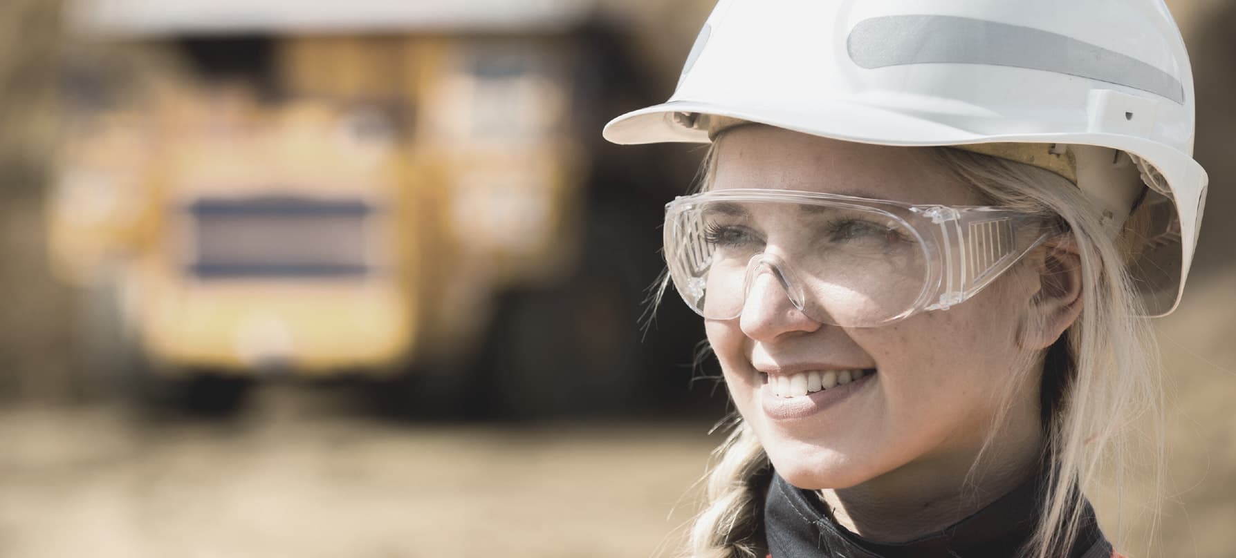 A worker in a hard hat and safety glasses on a mine site